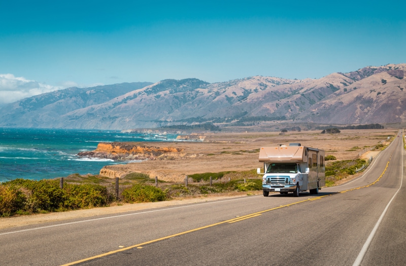 A large RV from one of the best RV rental companies drives along the California Highway 1
